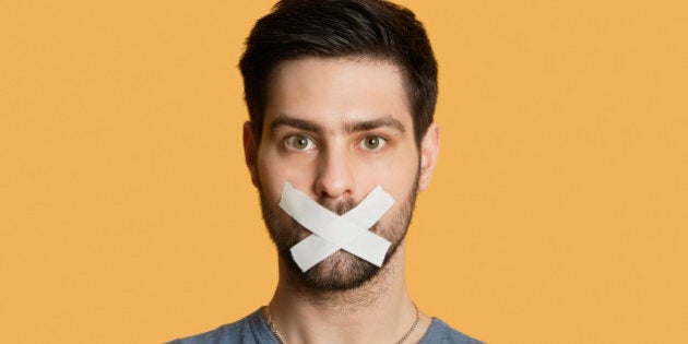 Portrait of a young man with tape on mouth over colored background