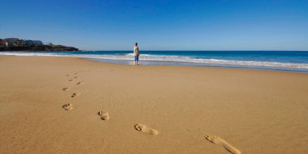 Woman standing a lone on a beach.