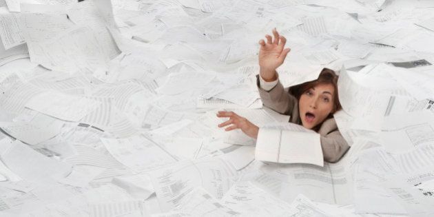 Mixed race businesswoman drowning in paperwork