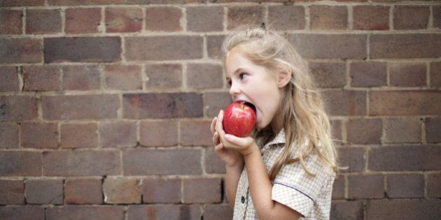 Young girl in school uniform eating an apple