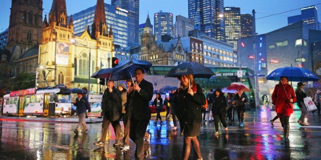 MELBOURNE, AUSTRALIA - JULY 31: People shelter from the rain under umbrellas as they cross the road from Federation Square on July 31, 2014 in Melbourne, Australia. Temperatures dropped and strong winds of over 100mk/h hit Melbourne this afternoon, bringing rain and hail across the state. (Photo by Scott Barbour/Getty Images)