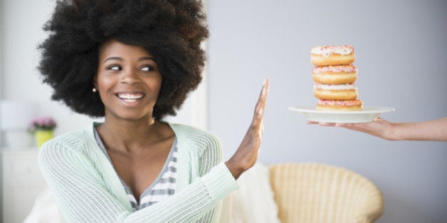 Mixed race woman refusing donuts