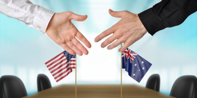 Two diplomats from United States and Australia extending their hands for a handshake on an agreement between the countries.