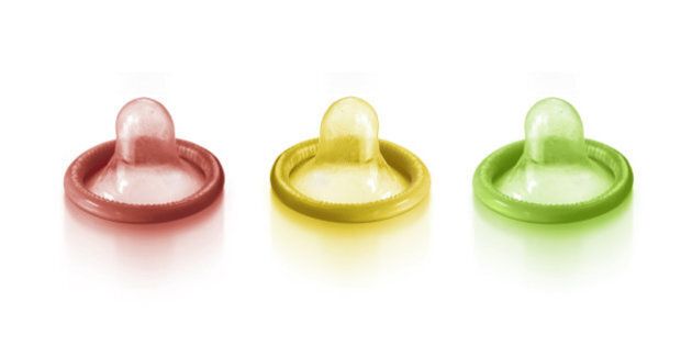 Red, yellow and green condom on white background.