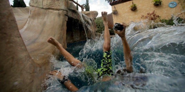 In this photo taken on Thursday, May 21, 2015, Jake Hall, 10, dives into a backyard pool in Long Beach, Calif. As residents struggle to reduce potable water consumption by 25 percent, the California Pool and Spa Association is promoting a campaign called Letâs Pool Together and aggressively lobbying water districts to quash proposed bans on filling pools and spas. (AP Photo/Chris Carlson)