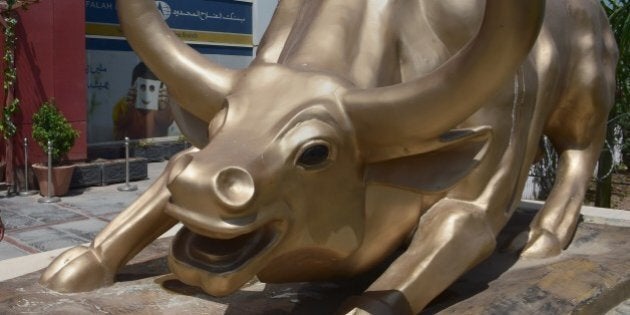 Pakistan workers walk past the bull at the Islamabad Stock Exchange (ISE) building in Islamabad on August...