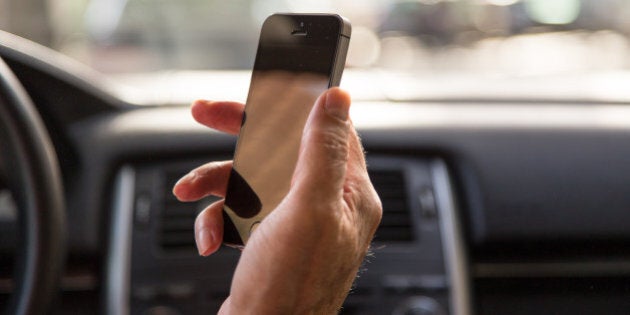 Man driving car and checking the smartphone in first person view.