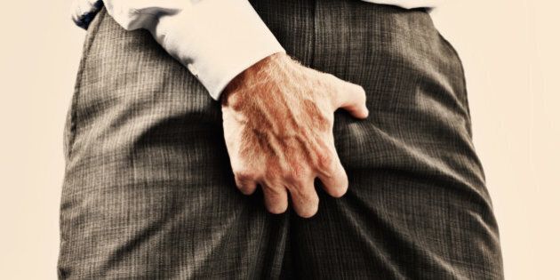 Cropped view of businessman in formal clothes grabbing his genitals through his clothes, maybe he's itchy but it's very vulgar behavior and sexist too!