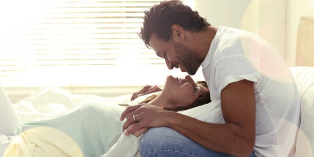 Loving interracial couple on their bed about to kiss each other.