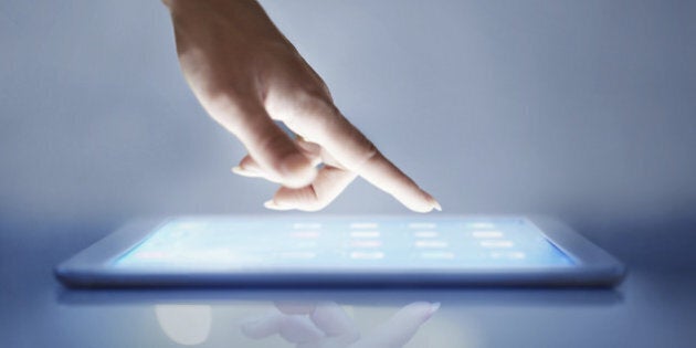 Cropped closeup of a woman's hand above a digital tablet