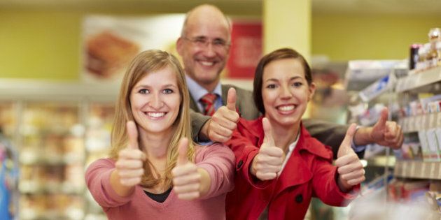 Germany, Cologne, Man and women showing thumbs up in supermarket