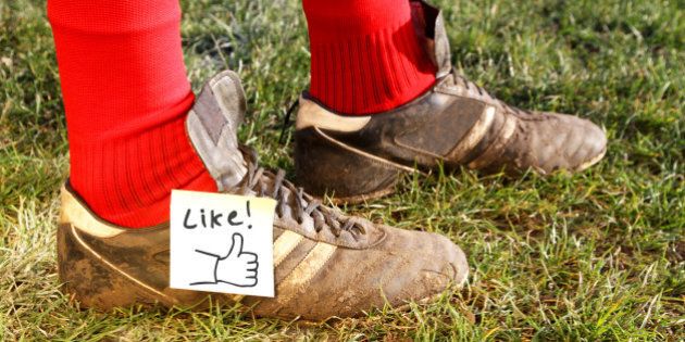 'Like' symbol on football players boots, while standing in a field ready to play.