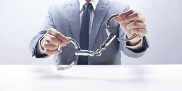 Businessman holding handcuffs at the desk.
