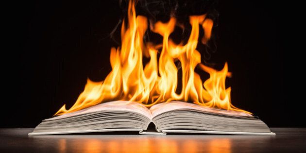 Open hard covered book engulfed in flame