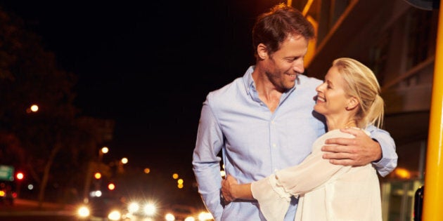 Couple embracing on city street at night, portrait