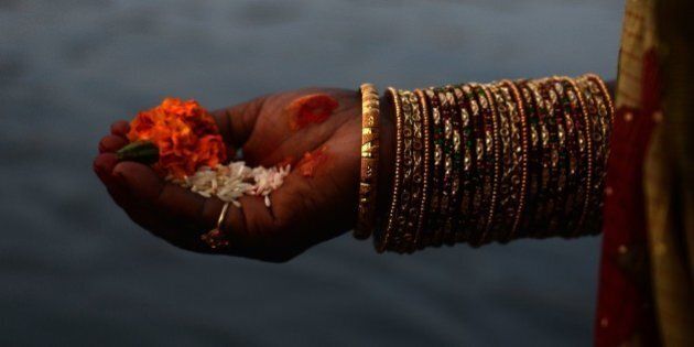 A Nepalese Hindu woman holds offerings as she worships the sun in the Bagmati River in Kathmandu on November17, 2015, during the Chhath Festival which honours the sun god. People pay their respects to both the rising and setting sun during the Chhath festival when people express their thanks and seek blessings from the forces of nature. AFP PHOTO / Prakash MATHEMA (Photo credit should read PRAKASH MATHEMA/AFP/Getty Images)