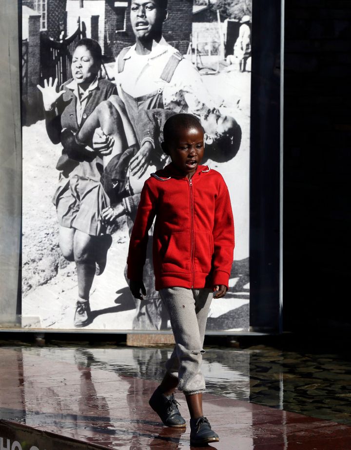 Behind a young boy at the Hector Pieterson Memorial in Soweto is the iconic photo of 13-year-old Hector Pieterson being carried after being shot by police during the 1976 Soweto uprising.