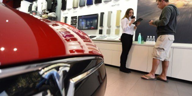 A salesrep (L) helps a customer pre-order the as yet unseen Tesla Model 3, in the Tesla store on the Third Street Promenade in Santa Monica, California, on March 31, 2016. / AFP / ROBYN BECK (Photo credit should read ROBYN BECK/AFP/Getty Images)