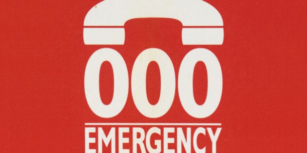 Sign indicating to call 000 in case of emergency, on the side of a phone booth in Sydney, Australia.