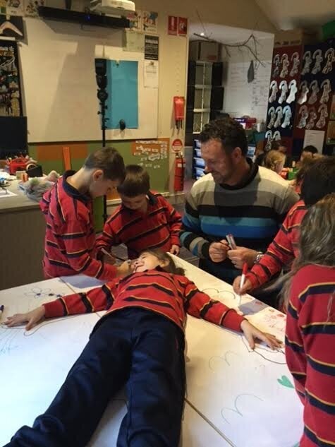 Teacher Jamie Shackleton supervising the kids tracing around one of their classmates...as you do.