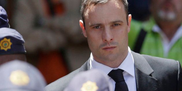 FILE - In this Friday, Oct. 17, 2014 file photo, Oscar Pistorius is escorted by police officers as he leaves the high court in Pretoria, South Africa. A South African official says Oscar Pistorius has been released from prison and placed under house arrest. Manelisi Wolela, a spokesman for South Africa's correctional services department, said the double-amputee Olympic runner who fatally shot his girlfriend on Valentine's Day 2013 was put under