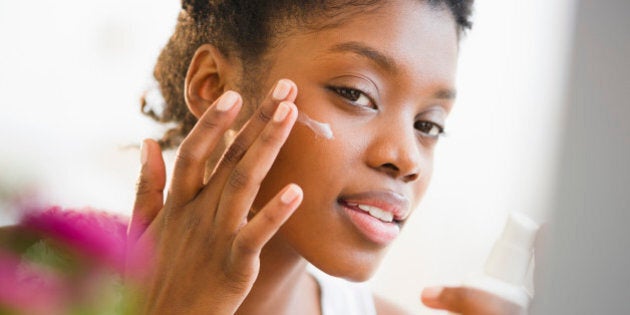 Black woman putting on face lotion