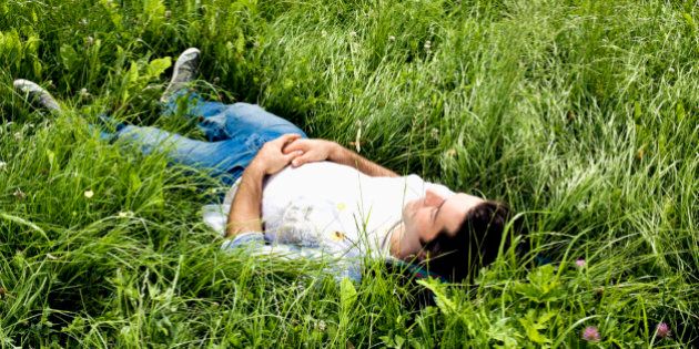 full body portrait of young man dozing in grass