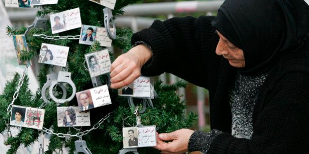 Lebanese Hana Yehya, mother of Mustafa Zakzouk who was detained in 1988 and believed to be still held in a prison in Syria, decorates a Christmas tree with handcuffs and photos of missing persons, in Beirut, Lebanon, Thursday, Dec. 22, 2005. Seventeen thousand people are still missing since the end of the 1975-90 Lebanese civil war. (AP Photo/Hussein Malla)