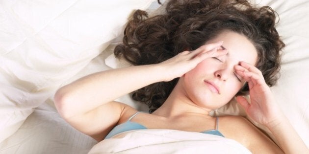 Woman in bed rubbing her eyes