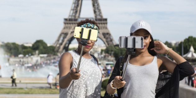 PARIS, FRANCE - AUGUST 06: Tourists take a selfie using a selfie stick in front of the Eiffel Tower on August 6, 2015 in Paris, France. Using a selfie stick has become a more and more common place among tourists but a number of high-profile attractions in Paris and other cities have started to ban them over fears of potential damage to exhibits. (Photo by Vanni Bassetti/Getty Images)