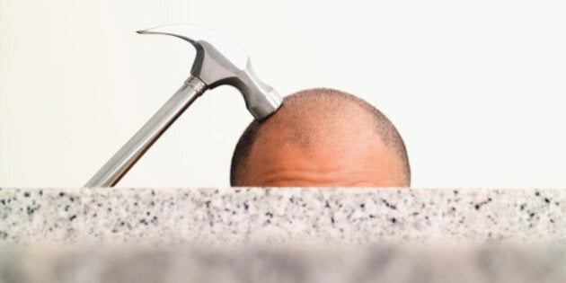 Hammer on top of man's shaved head, close-up