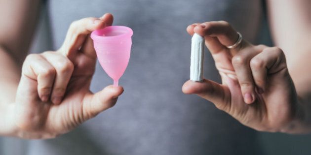 Young woman hands holding different types of feminine hygiene products - menstrual cup and tampons