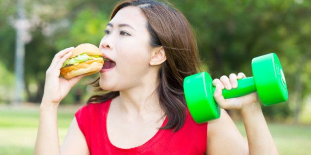 Asian woman eating hamburger with weight-lifting