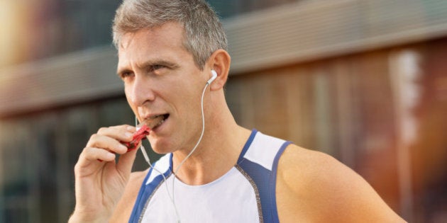 Portrait Of Fitness Mature Man Eating A Energy Bar Of Chocolate