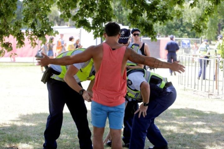 Police frisk a man for drugs at Melbourne's Stereosonic festival