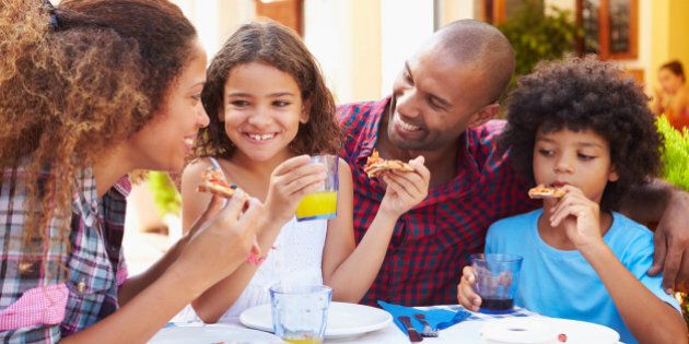 Family Eating Meal At Outdoor Restaurant Together, Smiling