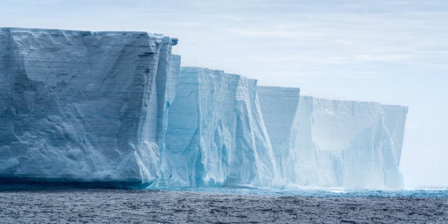 Massive flat topped iceberg floating in the Southern Ocean of Antarctica showing the weathered cracks and fissures on the sides