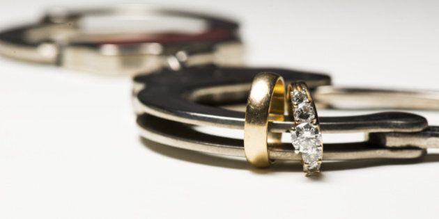 a close up of wedding rings and a handcuff showing people locked in love.