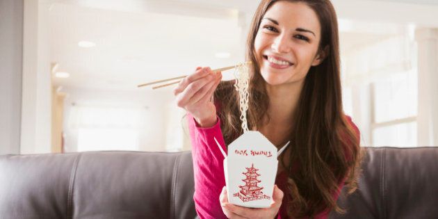 Caucasian woman eating Chinese food on sofa