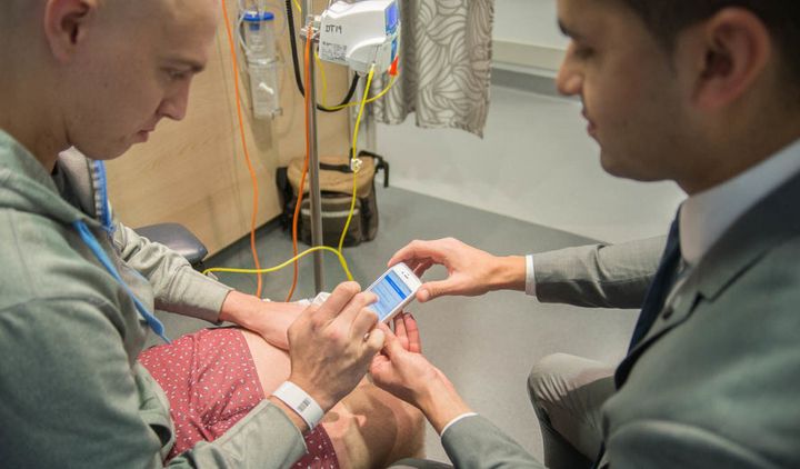 Pooviah shows Chris O'Brien Lifehouse patient Brendan Kennedy how the CancerAid app works.