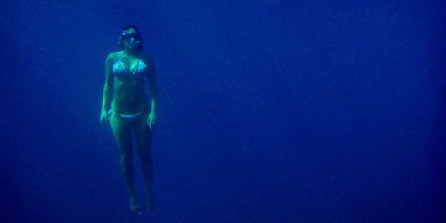 A female snorkeler rises from the depths of the ocean at Turtle Canyon in Hawaii.