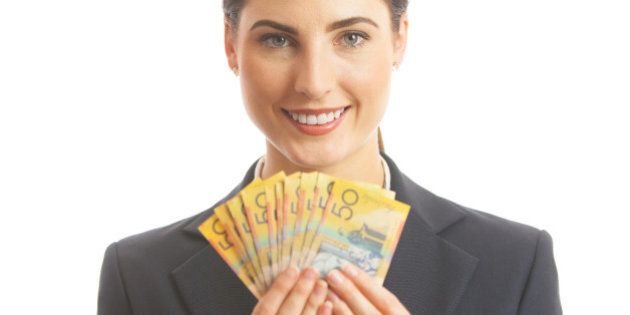 Close up of a happy business woman holding Australian cash. She is dressed in a corporate business suit, and is smiling and looking at camera. Studio shot on a white background.