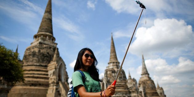 A tourist snaps a picture of herself with a selfie stick at Wat Phra Sri Sanphet, a temple in the ancient city of Ayutthaya, Thailand.