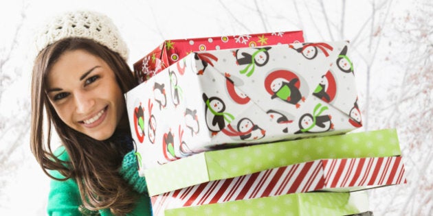 Caucasian woman holding Christmas gifts in snow