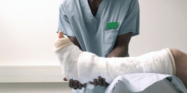Male nurse supporting man's leg wrapped in bandages