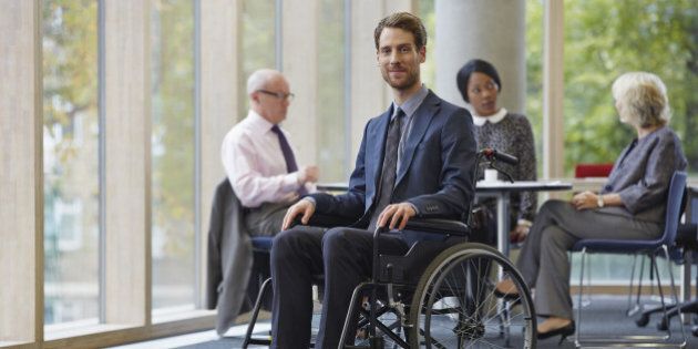 Businessman in wheelchair, meeting in background