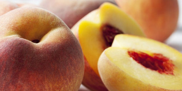 Whole and sliced peaches (Prunus persica) on white wooden table