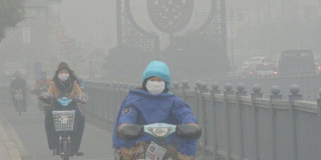 SUZHOU, CHINA - DECEMBER 07: (CHINA OUT) Cyclists wearing masks ride along a road in heavy smog on December 7, 2015 in Suzhou, China. China's National Meteorological Center (NMC) issued a yellow alert on Sunday as heavy smog will cover the country's northern regions in the following two days. (Photo by ChinaFotoPress/ChinaFotoPress via Getty Images)