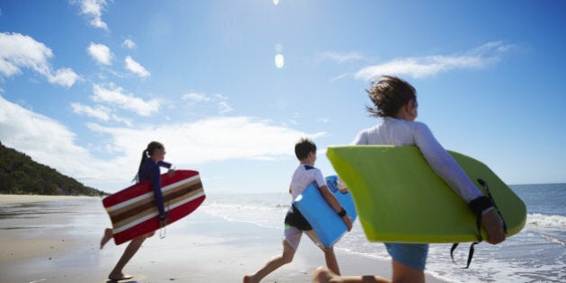 Three children running into the ocean