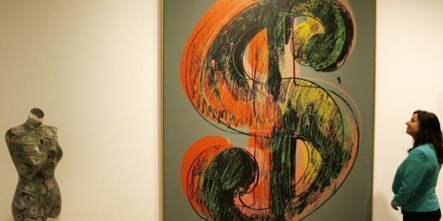 A woman looks at a piece of art entitled 'Dollar Sign, 1981,' an acrylic and silkscreen ink on canvas by US artist Andy Warhol, valued at 4-6 million British pounds (6-9 million US dollars, 5.4-8.2 million Euros) at Sotheby's auction house in London on June 8, 2015. Sotheby's are to offer a museum-quality private collection of 21 works by several artists inspired by the US dollar motif. AFP PHOTO/ADRIAN DENNIS RESTRICTED TO EDITORIAL USE, MANDATORY MENTION OF THE ARTIST UPON PUBLICATION, TO ILLUSTRATE THE EVENT AS SPECIFIED IN THE CAPTION (Photo credit should read ADRIAN DENNIS/AFP/Getty Images)